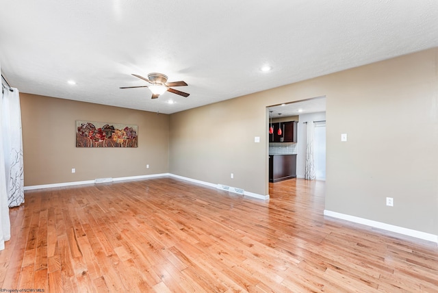 unfurnished room with ceiling fan, a textured ceiling, and light wood-type flooring