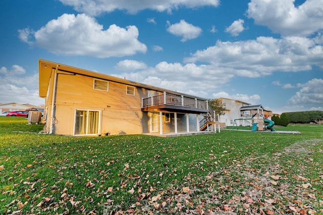 rear view of property with a lawn, a wooden deck, and central AC