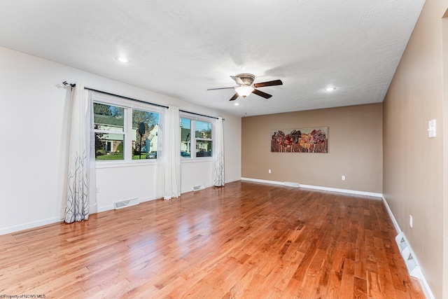 empty room featuring a textured ceiling, light hardwood / wood-style floors, and ceiling fan