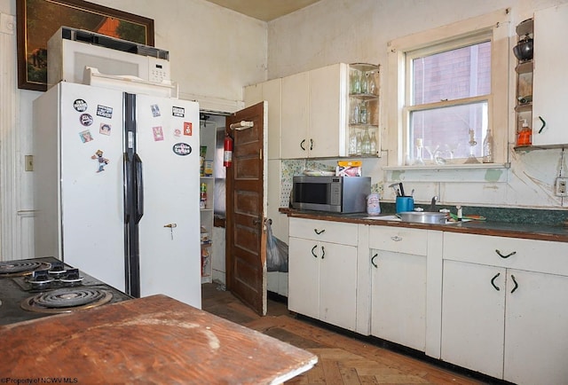 kitchen featuring dark parquet flooring, sink, white fridge, cooktop, and white cabinetry