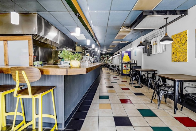 kitchen featuring a breakfast bar, kitchen peninsula, tile patterned floors, and hanging light fixtures