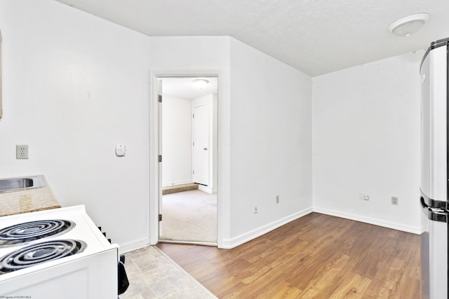 kitchen with white electric range, light wood-type flooring, a textured ceiling, and sink