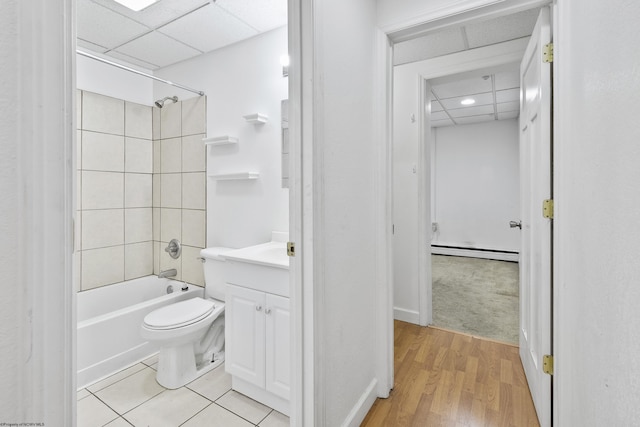 full bathroom featuring tiled shower / bath combo, baseboard heating, wood-type flooring, toilet, and vanity