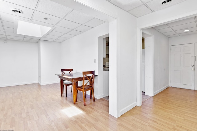 dining space featuring light wood-type flooring and a paneled ceiling