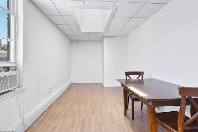 dining room featuring light wood-type flooring and a drop ceiling