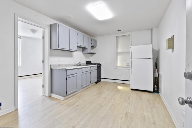 kitchen featuring gray cabinets, white fridge, light hardwood / wood-style flooring, and black range oven