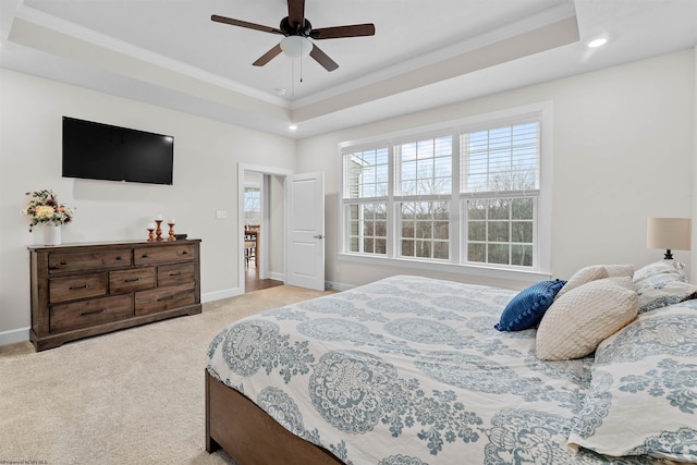 carpeted bedroom with a tray ceiling, ceiling fan, and ornamental molding