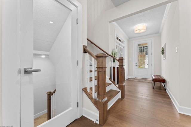 foyer with a textured ceiling, hardwood / wood-style flooring, and ornamental molding