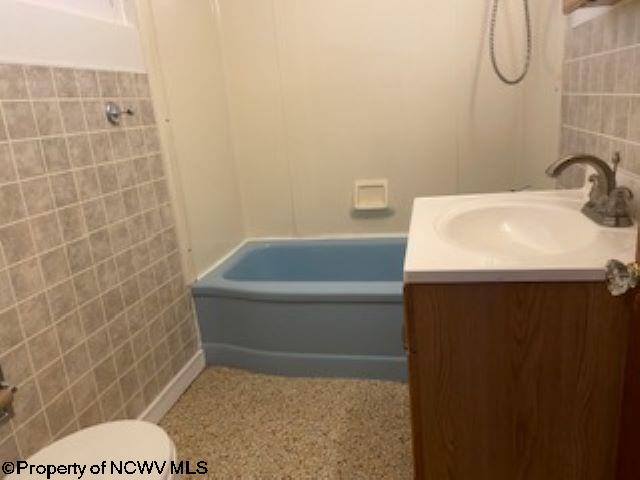 full bathroom featuring shower / bathtub combination, vanity, toilet, and tile walls