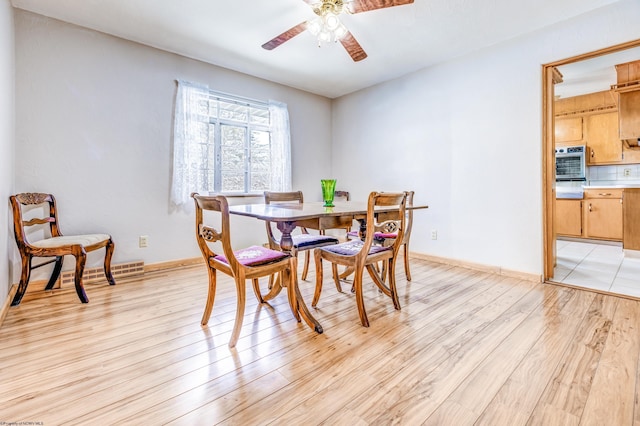 dining space with ceiling fan and light wood-type flooring