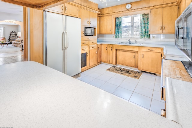 kitchen featuring white fridge, sink, light tile patterned floors, and black microwave