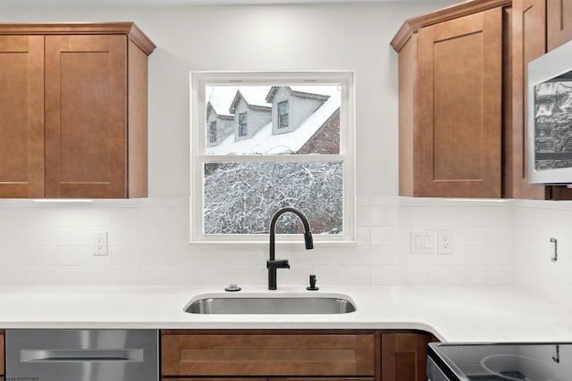 kitchen featuring decorative backsplash, dishwasher, and sink