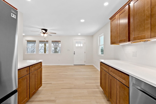 kitchen with tasteful backsplash, light wood-type flooring, stainless steel appliances, and ceiling fan