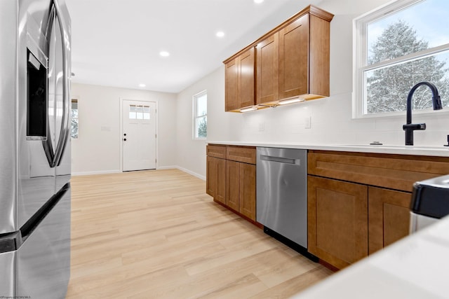 kitchen with decorative backsplash, light hardwood / wood-style floors, sink, and appliances with stainless steel finishes