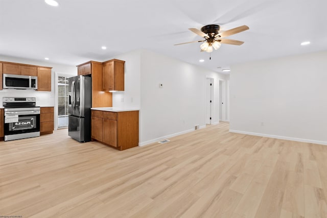 kitchen with light wood-type flooring, stainless steel appliances, and ceiling fan