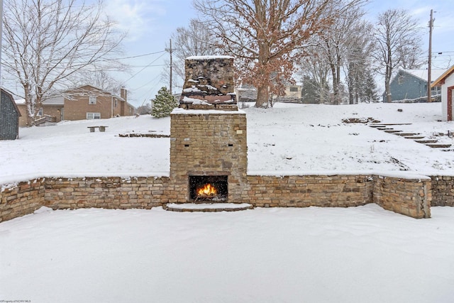 yard layered in snow featuring an outdoor brick fireplace