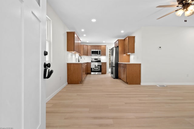 kitchen with ceiling fan, sink, stainless steel appliances, and light hardwood / wood-style flooring