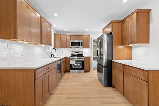 kitchen with backsplash, light wood-type flooring, sink, and appliances with stainless steel finishes