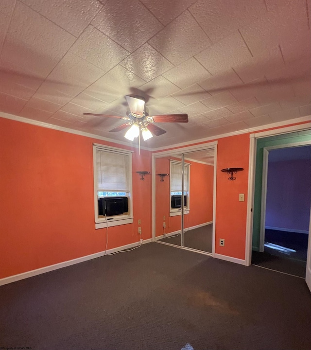 spare room with dark colored carpet, ceiling fan, cooling unit, and ornamental molding