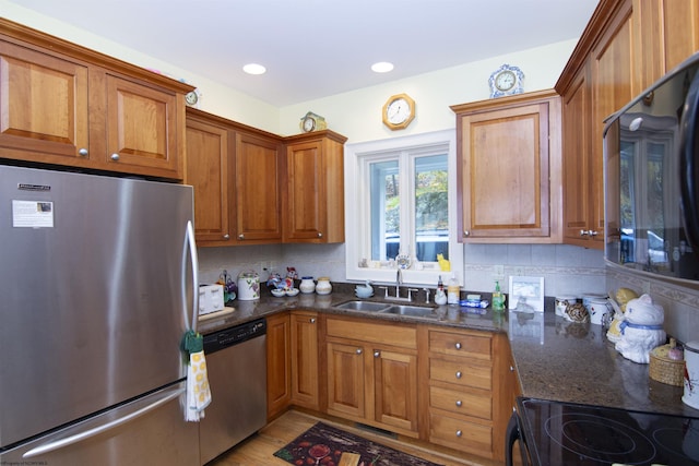 kitchen with decorative backsplash, appliances with stainless steel finishes, dark stone counters, and sink