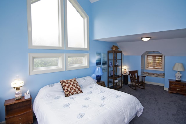 bedroom with multiple windows, dark carpet, and lofted ceiling