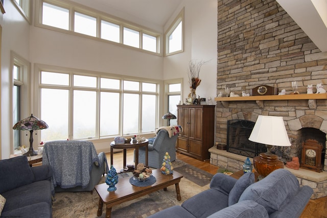 living room featuring a fireplace, a towering ceiling, and hardwood / wood-style flooring