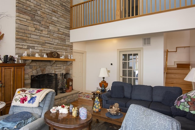 living room with a stone fireplace, wood-type flooring, and a towering ceiling