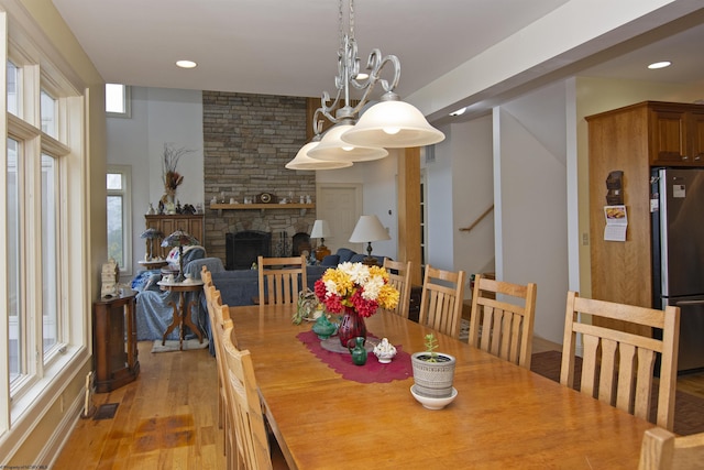 dining room with a fireplace, an inviting chandelier, and light hardwood / wood-style flooring