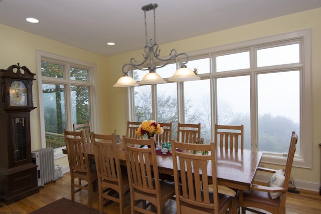 dining room with radiator heating unit, light wood-type flooring, and an inviting chandelier