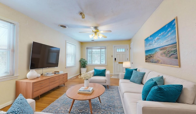 living room with ceiling fan, light wood-type flooring, and a wealth of natural light