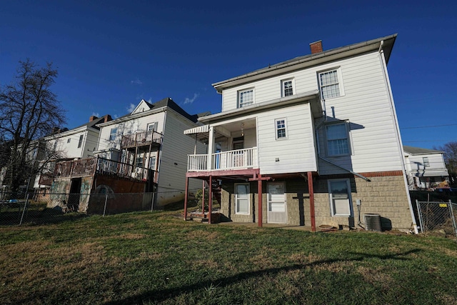 rear view of property with a balcony and a lawn