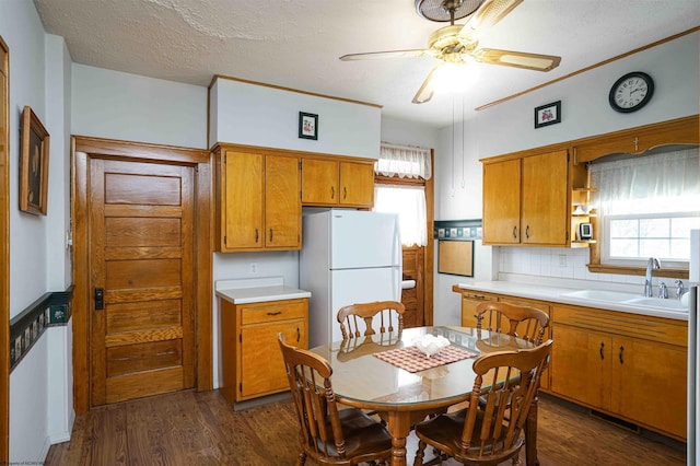 kitchen featuring dark wood-type flooring, white refrigerator, sink, decorative backsplash, and ceiling fan