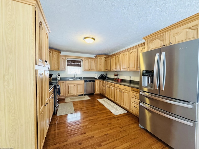 kitchen featuring sink, stainless steel appliances, a textured ceiling, and wood-type flooring