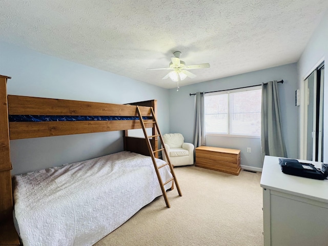 bedroom with a closet, a textured ceiling, light colored carpet, and ceiling fan