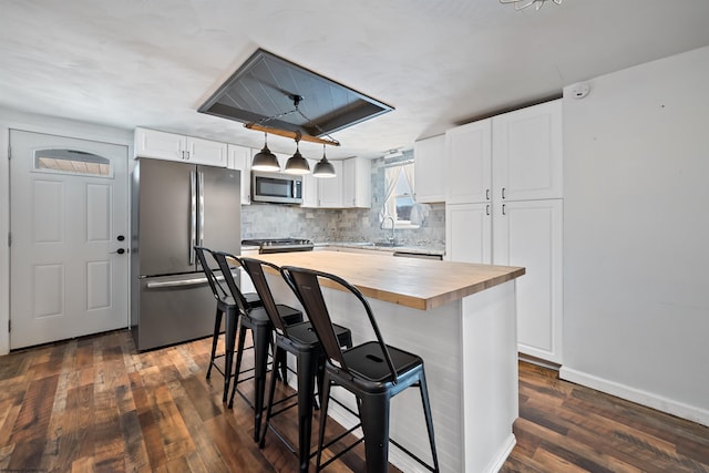 kitchen featuring appliances with stainless steel finishes, a center island, butcher block countertops, and white cabinetry