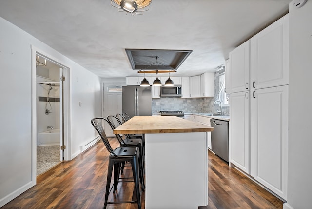 kitchen with appliances with stainless steel finishes, a breakfast bar, white cabinets, a center island, and butcher block counters