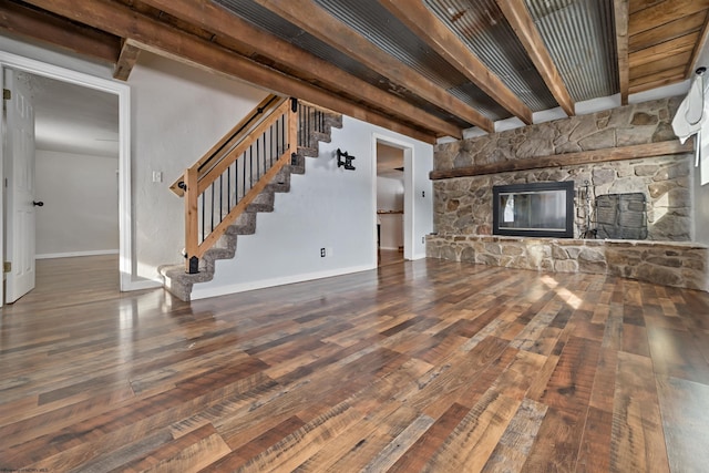 unfurnished living room with beamed ceiling, wood-type flooring, and a stone fireplace