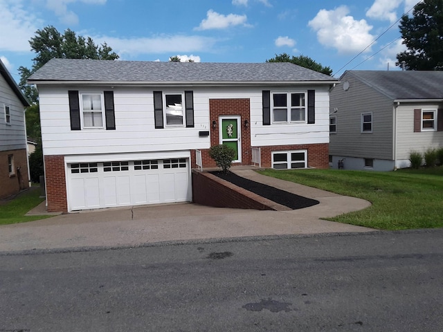 raised ranch with a shingled roof, brick siding, a garage, and a front lawn