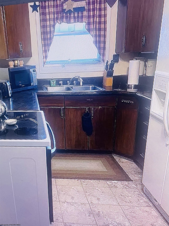 kitchen with dark brown cabinets, refrigerator, white range, and sink