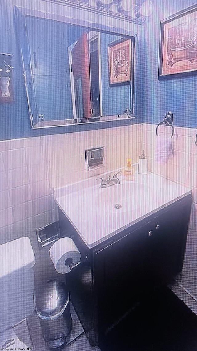 bathroom featuring vanity, toilet, and tile walls