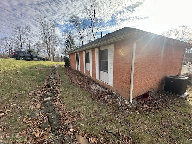 view of side of property featuring central air condition unit and a yard