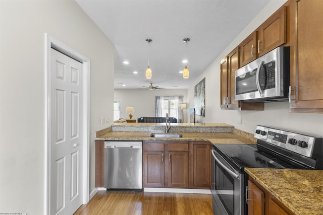 kitchen with hanging light fixtures, sink, light hardwood / wood-style flooring, ceiling fan, and appliances with stainless steel finishes