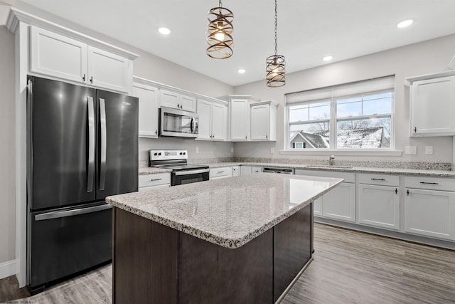 kitchen featuring white cabinets, appliances with stainless steel finishes, a center island, and hanging light fixtures