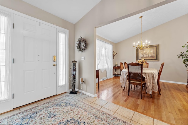 tiled entrance foyer with plenty of natural light, a chandelier, and lofted ceiling