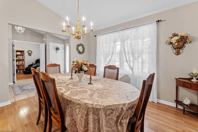 dining area with vaulted ceiling, light hardwood / wood-style floors, and a chandelier