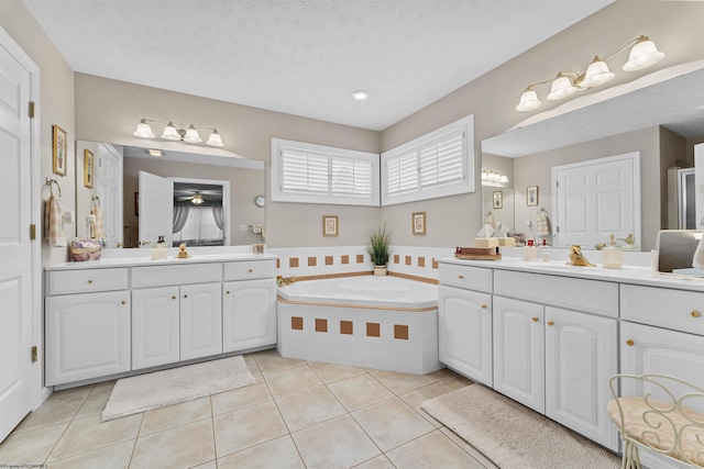 bathroom with tile patterned floors, tiled bath, vanity, and a textured ceiling