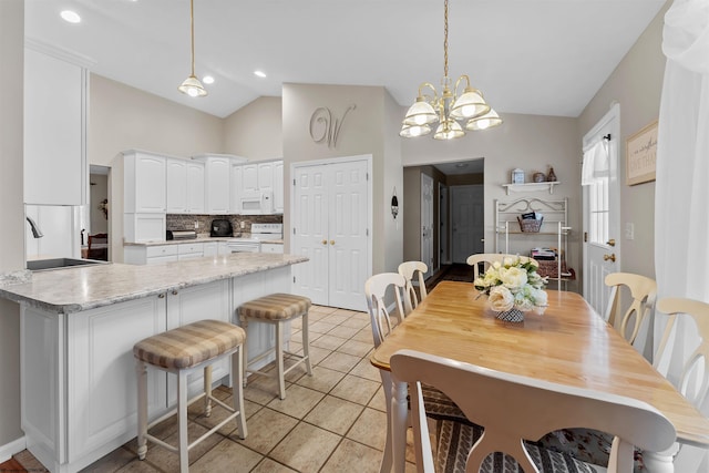 tiled dining space featuring sink, lofted ceiling, and a notable chandelier