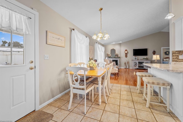 tiled dining space with vaulted ceiling and an inviting chandelier