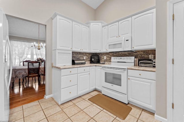 kitchen featuring a chandelier, white cabinets, light tile patterned flooring, and white appliances