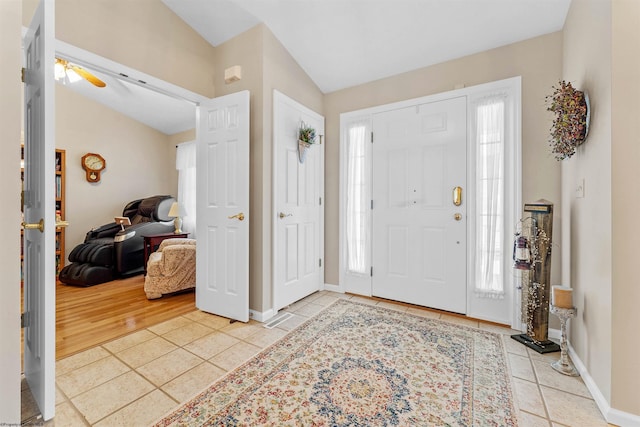 entryway featuring ceiling fan, light tile patterned flooring, and vaulted ceiling